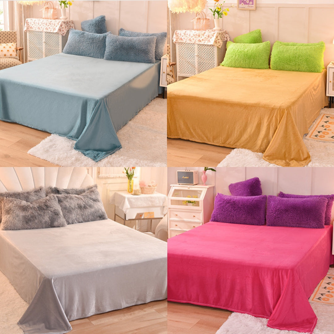 Four different colored bedspreads on a bed with matching pillows in a bedroom setting.
