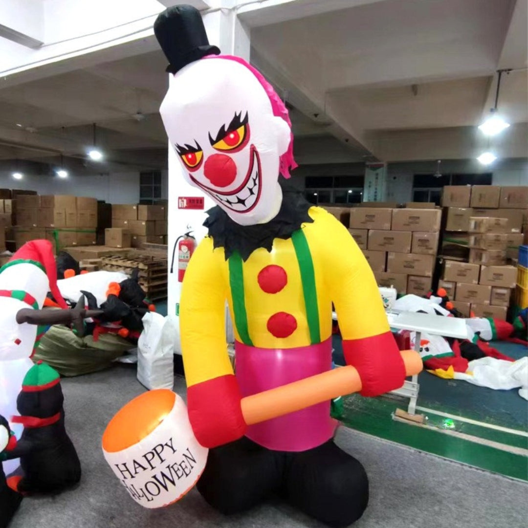 Inflatable clown decoration with a 'Happy Halloween' bucket in a warehouse setting.