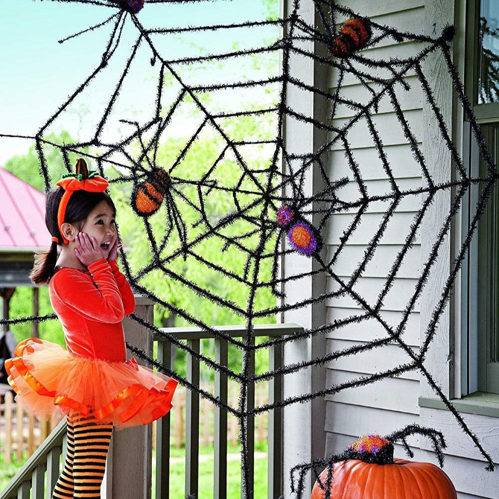 Halloween decoration with spider web, pumpkins, and child in costume.