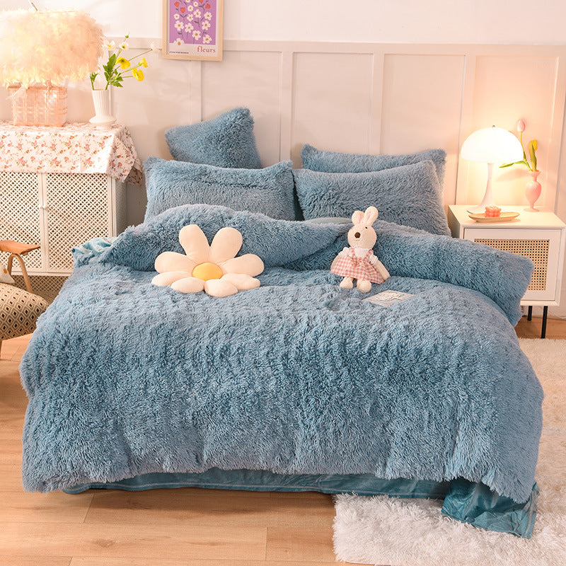 Blue fluffy comforter set on a bed in a bedroom setting with decorative pillows and plush toys.