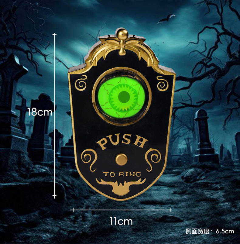 Decorative doorbell with green eye design in a spooky graveyard setting